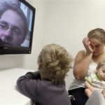 An inmate is shown on a television screen as his family visits him via video conferencing at a county jail in Texas. About 1.7 million children have a parent behind bars.